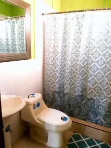 y baño con aseo y cortina de ducha. en Hostal Doña Marta en San Salvador