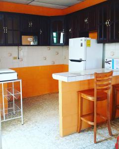 a kitchen with a counter and a white refrigerator at Hostal Doña Marta in San Salvador