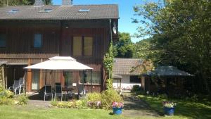 ein Haus mit einem Regenschirm, einem Tisch und Stühlen in der Unterkunft Ferienhaus Königreich - Dreistegen in Monschau