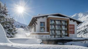 ein schneebedecktes Gebäude mit Sonne im Hintergrund in der Unterkunft Hotel Gotthard-Zeit in Obergurgl