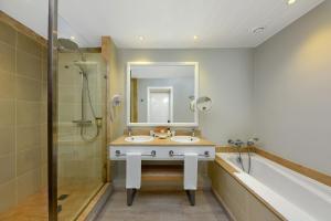 a bathroom with a tub, sink, and mirror at Mauricia Beachcomber Resort & Spa in Grand Baie