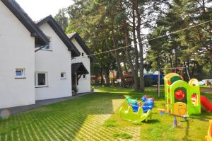 a yard with childrens playground equipment and a house at Ferienhaus Holiday Home Domki RAJ in Jarosławiec