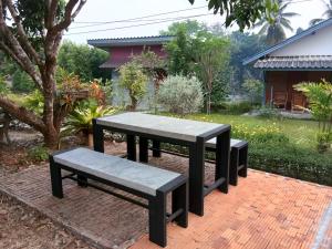 una mesa de picnic y bancos en un patio de ladrillo en Ban Suan Sukjai Mae Sariang, en Mae Sariang
