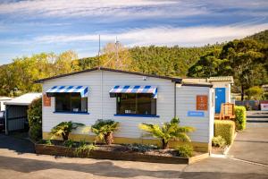 una casa blanca con toldo azul y blanco a rayas en Discovery Parks - Mornington Hobart, en Hobart