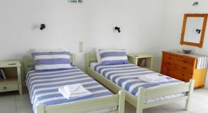2 łóżka w pokoju z lustrem i komodą w obiekcie Explorer's Rest w Argasio