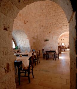 a restaurant with tables and chairs in a stone wall at Masseria Chiancone Torricella in Martina Franca
