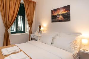 a white bedroom with a bed and a window at Apartment Mari in Dubrovnik