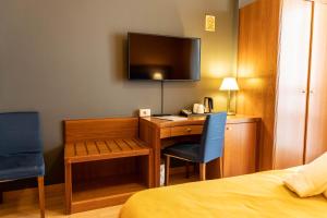 
a bedroom with a bed, chair, desk and television at Hotel Berlino in Milan
