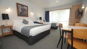 a hotel room with two beds and a table at ASURE Christchurch Classic Motel & Apartments in Christchurch