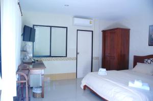 a bedroom with a bed and a desk and a television at Thararin Villa in Ban Doem Bang