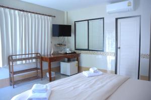 a bedroom with a bed and a desk and a television at Thararin Villa in Ban Doem Bang
