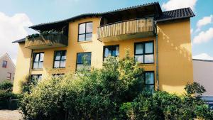 a yellow building with a balcony on top of it at Pension Genat in Wedemark