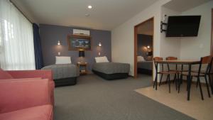 um quarto de hotel com duas camas e uma mesa em ASURE Christchurch Classic Motel & Apartments em Christchurch