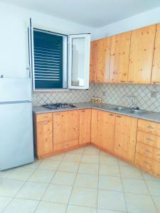 レウカにあるCasa vacanza Leucaのキッチン(木製キャビネット、白い冷蔵庫付)