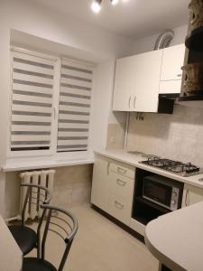 a kitchen with white cabinets and a stove top oven at Very nice Apartment in L'viv in Lviv