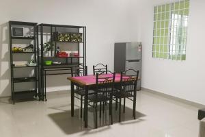 cocina con mesa, sillas y nevera en HomezStay Airport Miri, en Miri