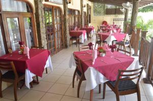 uma fila de mesas num restaurante com toalhas de mesa cor-de-rosa em Coco D'or Hotel Seychelles em Beau Vallon