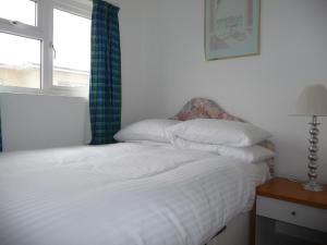 a bedroom with a white bed with a window at 151 Perran Sands in Perranporth