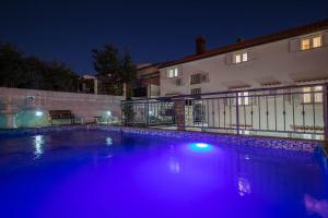 a swimming pool with blue lights in front of a house at Apartments Baretić in Crikvenica