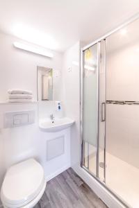 a white bathroom with a shower and a toilet at Brit Hotel Macon Nord Autoroute du Soleil in Mâcon