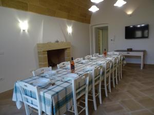 a room with a long table with white chairs at Dimora Rizzo con tappeti di pietra in Leuca