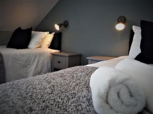 um quarto com 2 camas com lençóis brancos e almofadas em Seaview House Bed and Breakfast em Larne