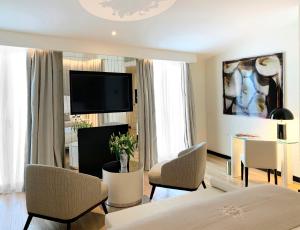 a living room with a bed and chairs and a television at Rosa Grand Milano - Starhotels Collezione in Milan