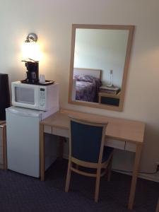 a room with a desk with a microwave and a mirror at Rider's Motor Inn in Kamloops