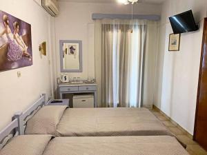 a bedroom with two beds and a tv on the wall at Sunshine Pension in Pythagoreio