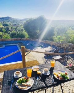 una mesa con comida y bebida y vistas a la piscina en Villa Monte da Alfarrobeira en Estói