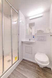 a white bathroom with a toilet and a shower at Brit Hotel Macon Nord Autoroute du Soleil in Mâcon