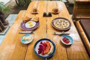 una mesa de madera con platos de desayuno en Mandalika Cottage, en Gili Trawangan