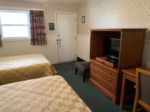a hotel room with two beds and a flat screen tv at The Lionstone Inn Motel and Cottages in Pictou