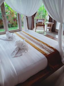 uma cama com lençóis brancos e toalhas em purnama fullmoon resort em Ubud
