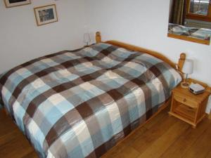 a bed with a plaid blanket and a night stand at Chalet Sandrine in Grächen