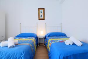 two beds in a room with blue sheets at Rosas en la Balconada & Apartment with Parking in Córdoba Historic Center in Córdoba