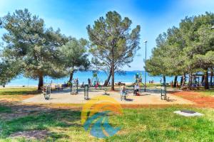 a park with trees and people on the beach at Apartments Valbandon 28 in Fažana