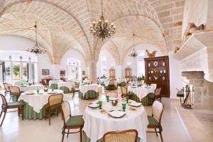 uma sala de jantar com mesas e cadeiras e um lustre em Masseria San Domenico em Savelletri di Fasano