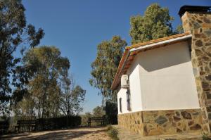 un pequeño edificio blanco con árboles en el fondo en Casa Rural Casa de las Aves, en Orellana la Vieja