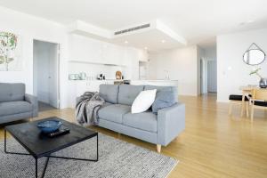 a living room with a couch and a table at Minimalist Penthouse Condo with Skyline Vistas in Perth