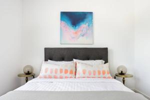 een slaapkamer met een groot bed met roze en witte kussens bij Minimalist Penthouse Condo with Skyline Vistas in Perth