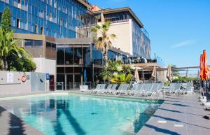 une piscine avec des chaises et un bâtiment dans l'établissement Novotel Marseille Vieux Port, à Marseille