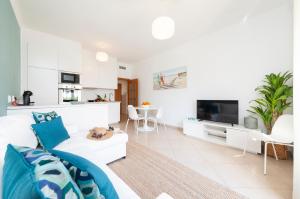uma sala de estar branca com um sofá e uma televisão em Oura BlueSea Apartment em Albufeira