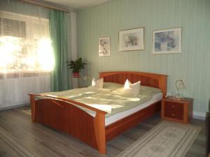 sypialnia z drewnianym łóżkiem i białymi poduszkami w obiekcie Maria Apartman w Hévízie