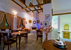 a living room with a table and chairs and a fireplace at Alkifron Hotel in Kala Nera