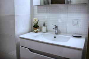 a white sink in a white bathroom with flowers at Apartamenty Polanka in Poznań