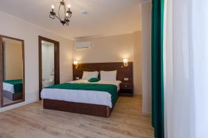a bedroom with a large bed with a green blanket at HOTEL BLOOM in Batumi