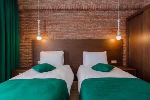 two beds with green pillows sitting next to a brick wall at HOTEL BLOOM in Batumi