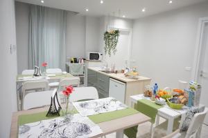 una cocina con mesas blancas, sillas blancas y una encimera en Borgo 22, en Catania