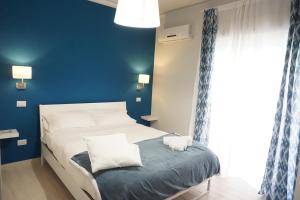 a bedroom with a white bed and a blue wall at Borgo 22 in Catania